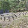 View 2 of several benches sitting in front of a small stage with trees in the background.