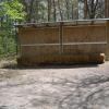 A small hay-filled wall that has hay bales in front of it.