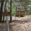 A sign that says "Caution: Archery Range" sits in front of several benches and a small hay-filled wall that has hay bales in front of it.