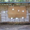 A small wall filled with hay that has large pieces of cardboard and paper plates affixed to it.