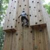 A person climbs a tall wooden climbing tower.