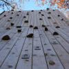 Close-up of a tall wooden climbing tower, featuring several footholds every couple feet.