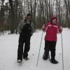 A man walks next to a young girl who is snowshoeing.