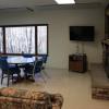 White Pine Lodge common area, with a television and fireplace in one corner, and a table and chairs surrounded by a couple couches.