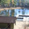 A green boat house and wooden dock on a lake in fall.