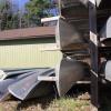 Canoes are stacked on top of and next to each other on a wooden structure.