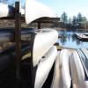 Canoes are stacked on top of and next to each other on a wooden structure.