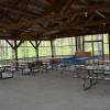 Screened-in Red Pine Pavilion interior, featuring overhead lights and seven picnic tables.