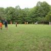 Several children and a few adults play a game on the sports field.