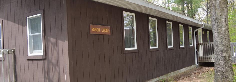A brown rectangular building featuring a sign that says "Birch Lodge."