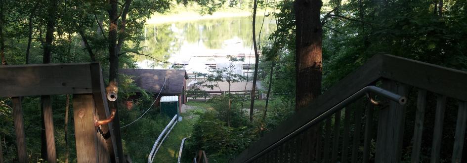 A wooden stairway leads down to a dock on a lake.