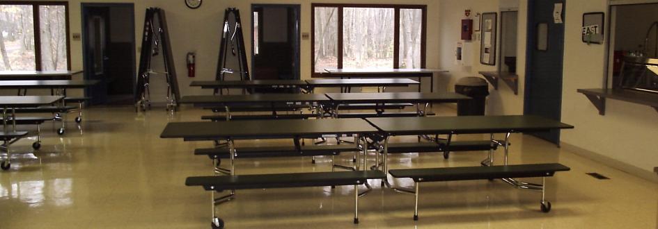 Several rows of tables line a cafeteria.